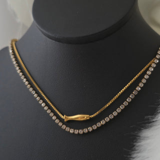 Pearl and Fish charm Gold necklace with clear stones on a black stand