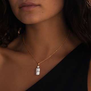 Close-up of a person wearing a 18k gold waterproof necklace with a Moissanite and Baroque Pearl pendant
