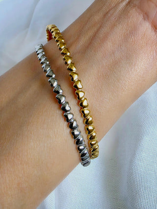 Hearts in a row design on a open cuff bracelets in a choice of 18k gold plating or sterling silver plating on stainless steel.